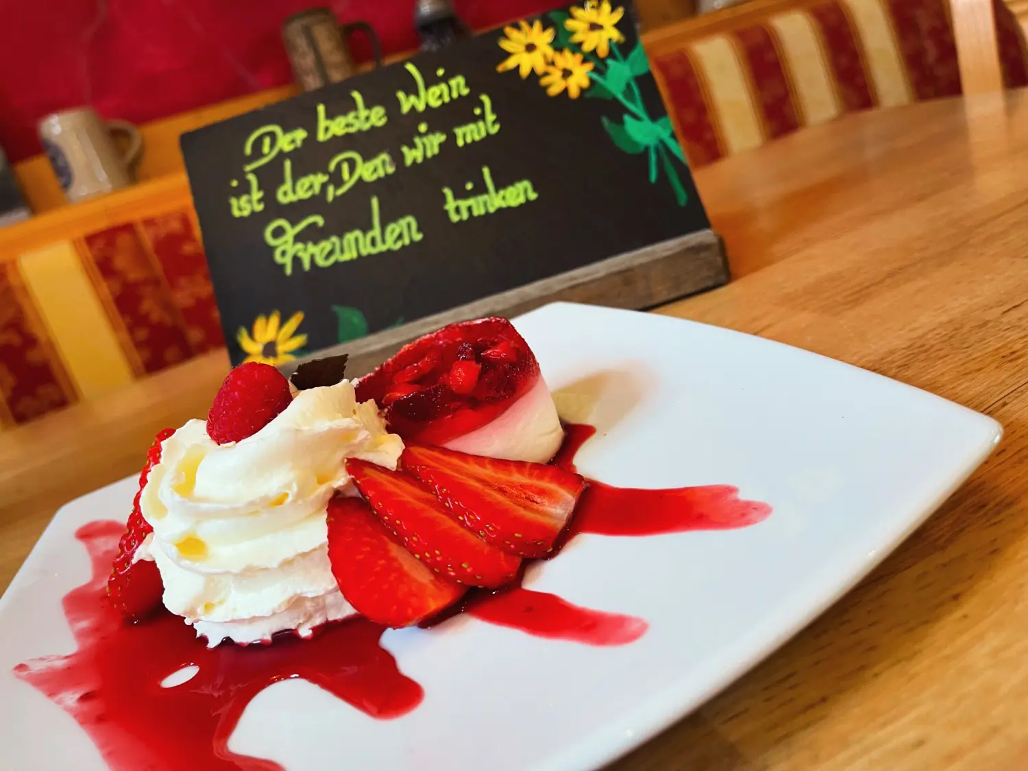 Ein Erdbeerkuchen oder ein ähnliches Dessert mit Schlagsahne und frischen Erdbeeren vom Restaurant Topinambur