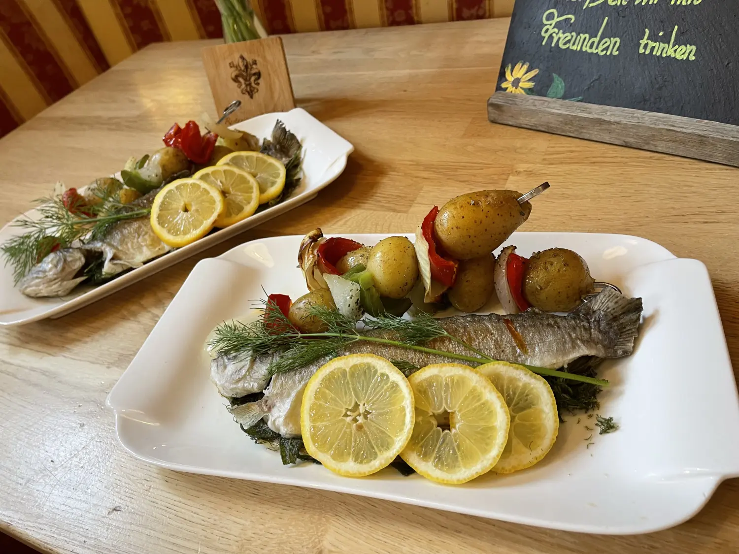 Ein Tellergericht mit einem ganzen gebratenen oder gegrillten Fisch vom Restaurant Topinambur