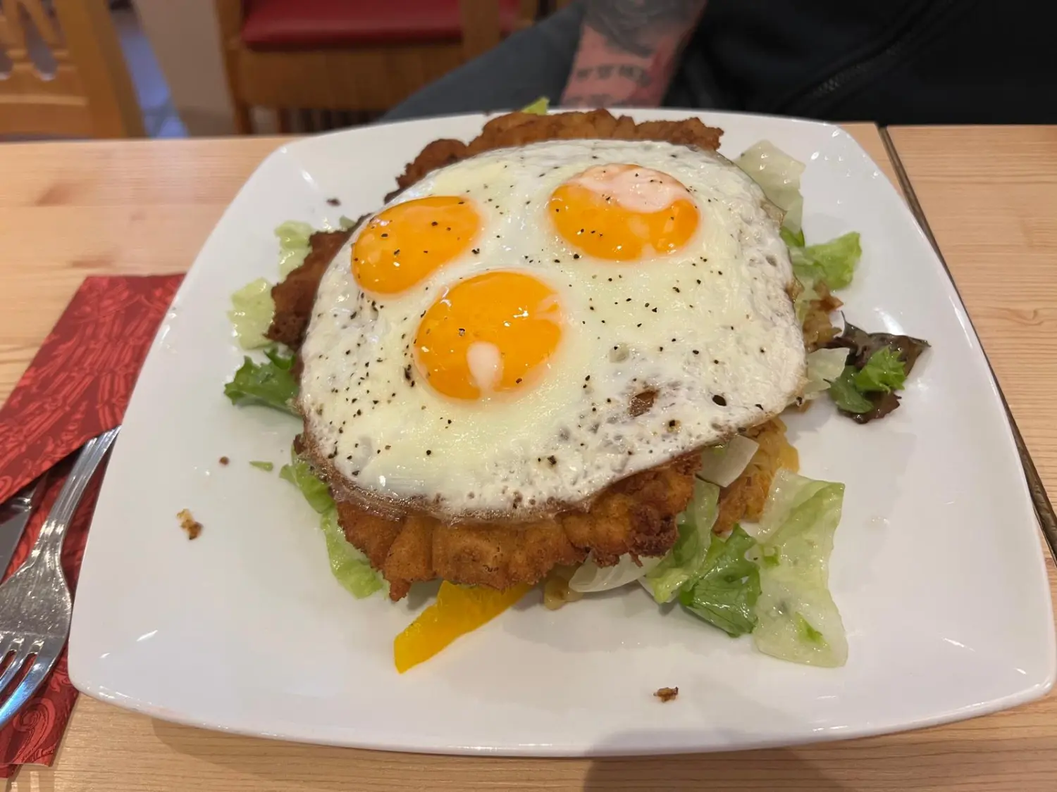 Eine Schnitzelvariation mit Spiegeleiern und Tomatenwürfeln, garniert mit Kräutern. Restaurant Topinambur