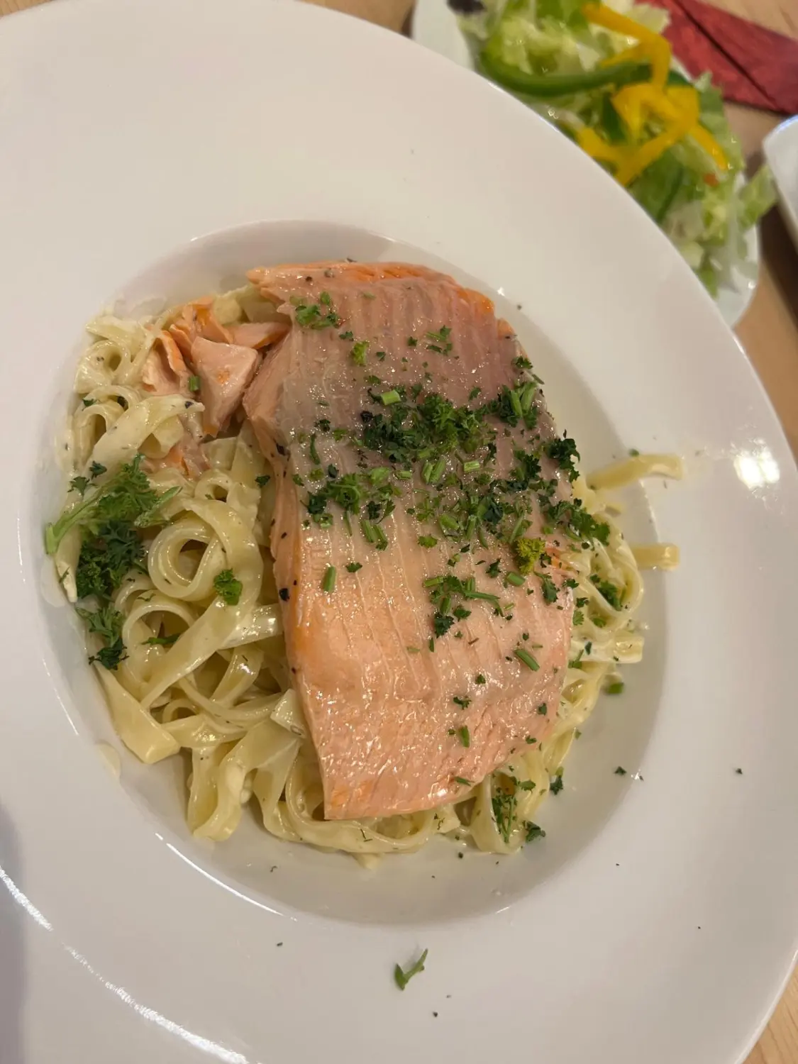 Pasta mit einem großen Stück gekochtem Lachs, garniert mit frischen Kräutern. Restaurant Topinambur