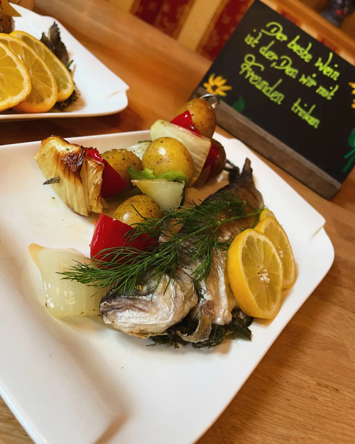 Ein Tellergericht mit einem ganzen gebratenen oder gegrillten Fisch vom Restaurant Topinambur