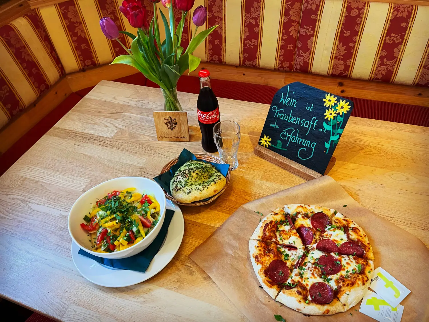 Ein Hähnchen-Gemüse-Gericht, serviert in einer weißen Schüssel. Und Pizza vom Restaurant Topinambur